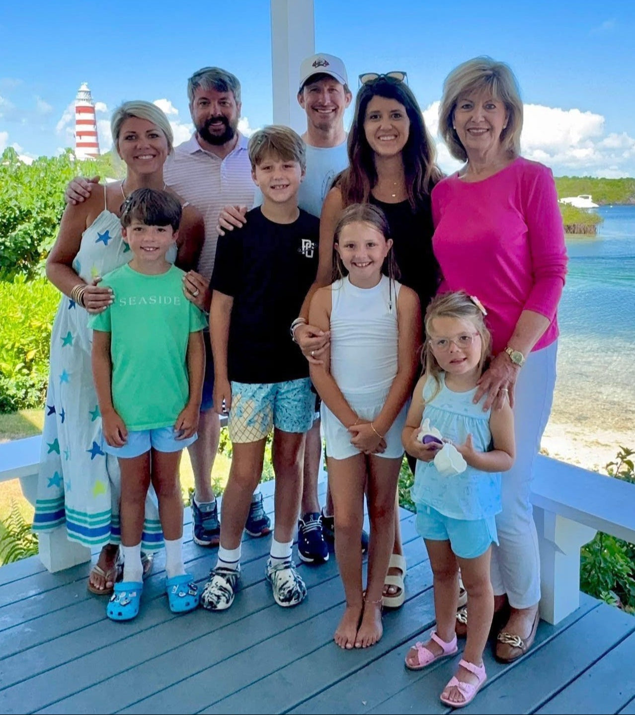 Family posing on a deck with a scenic background of water and sky.